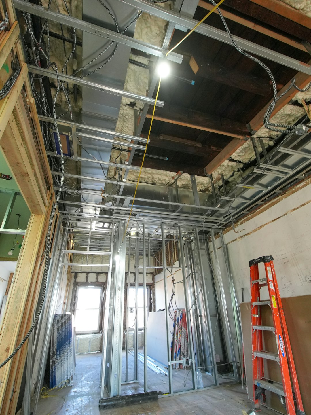A three-story brownstone stands in mid-transformation, captured at the raw and honest “before” stage of a full interior renovation. These images document a moment that usually disappears once the walls are closed and the finishes are installed — exposed framing, stripped ceilings, rough staircases, and open corridors that reveal the building’s original structure and hidden history. Light spills in through skylights and tall windows, cutting through layers of dust and unfinished surfaces, creating a quiet contrast between decay and renewal. The space feels both industrial and intimate: narrow