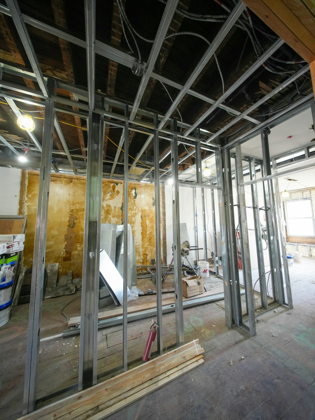 A three-story brownstone stands in mid-transformation, captured at the raw and honest “before” stage of a full interior renovation. These images document a moment that usually disappears once the walls are closed and the finishes are installed — exposed framing, stripped ceilings, rough staircases, and open corridors that reveal the building’s original structure and hidden history. Light spills in through skylights and tall windows, cutting through layers of dust and unfinished surfaces, creating a quiet contrast between decay and renewal. The space feels both industrial and intimate: narrow